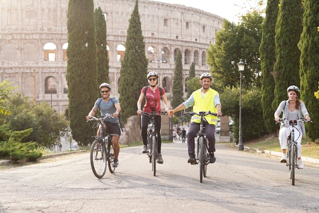 Image of a people biking in front of the colosseum in Rome