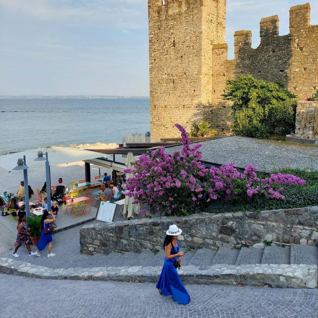 Image of a woman walking with a scenery composed of a castle and the sea