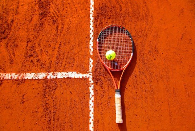 Image of a tennis racket on a clay surface to make your Italian dream come true.