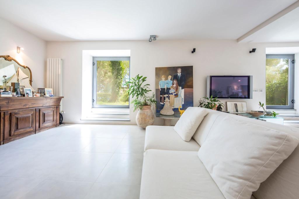 Image of the living room of a villa in Italy with a white cough and paintings