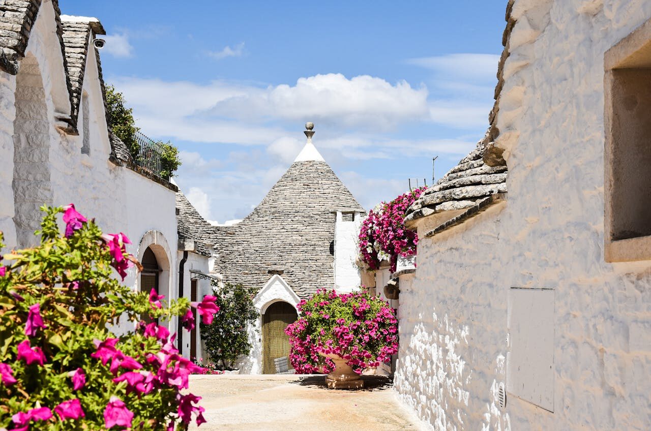 Image of a trullo house with flower in the surrondings